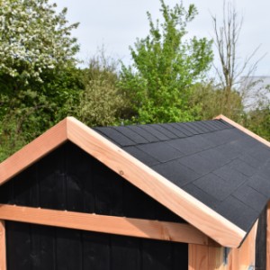 Das Dach der Hundehütte ist mit schwarzen Dachschindeln versehen