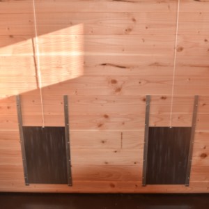 An der Seite des Stalls befinden sich 2 Auslaufklappen, die mit einer Schnur einfach geöffnet und geschlossen werden können.